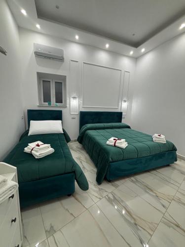 una camera da letto con due letti verdi e una parete bianca di Sasy Home a Napoli
