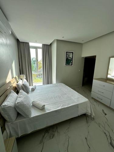 a large bed in a room with a window at Koko Beach - Blue sky house in Vila Praia Do Bilene