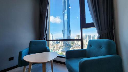 two chairs and a table in a room with a large window at Opus Residences Kuala Lumpur by Infini Suites in Kuala Lumpur