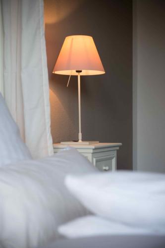 a lamp sitting on a table next to a bed at Botanico Finkenrech Hotel&Restaurant in Eppelborn