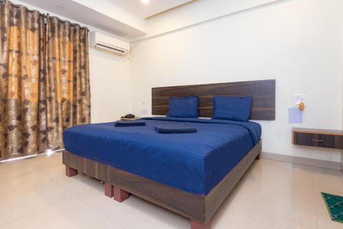 a bedroom with a large bed with blue sheets and blue pillows at HOTEL AVISHA Residency in Marmagao