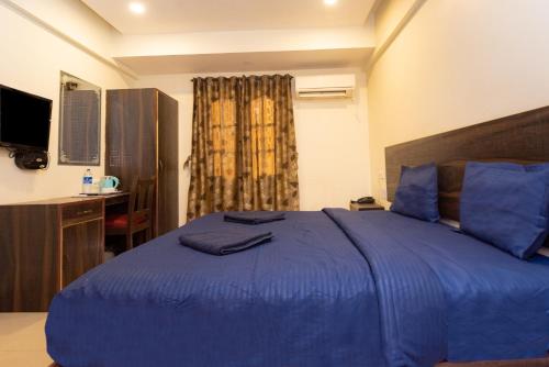 a bedroom with a blue bed and a television at HOTEL AVISHA Residency in Marmagao