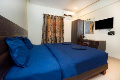 a bedroom with a blue bed and a television at HOTEL AVISHA Residency in Marmagao