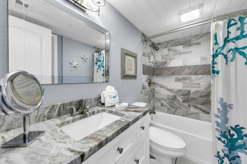 a bathroom with a sink and a toilet and a mirror at The Shores Townhome #116 in Carillon Beach