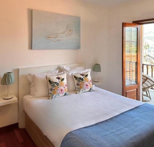 a bedroom with a bed with white sheets and pillows at Casa da Touça in Arcos de Valdevez