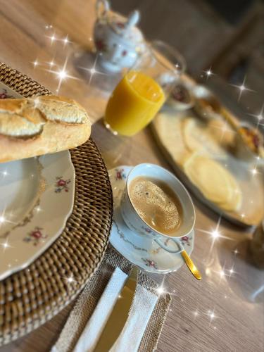 a table with a cup of coffee and a plate of bread at Au Petit Bonheur de Lorigné in Lorigné