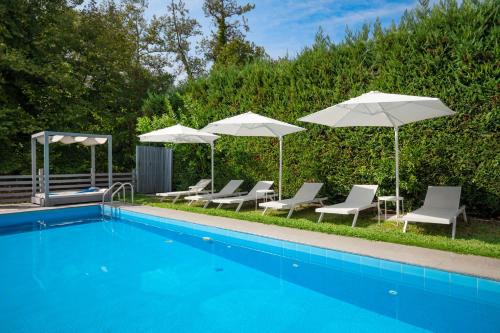 a pool with chairs and umbrellas and a group of chairs and tables at Aristi House in Olympiada