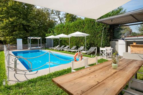 a pool with a wooden table in a backyard at Aristi House in Olympiada