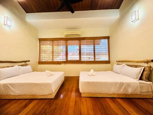 two beds in a room with wooden floors and a window at New Takekaze Retreat 竹风之家 for 14 pax at Central Penang in George Town