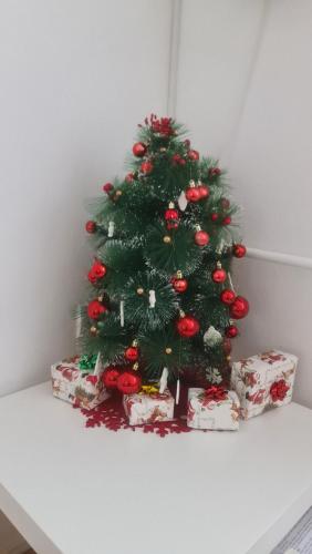 a christmas tree sitting on a table with presents at Apartman Zlatovo Stan Na Dan in Požarevac