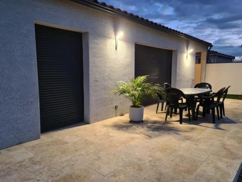 un patio avec une table et des chaises et un bâtiment dans l'établissement Charmante villa à Pezens, à Pezens