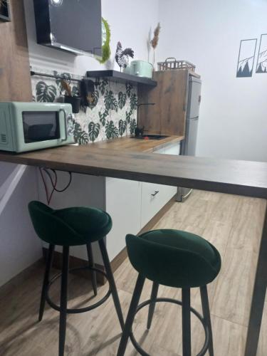 a kitchen with a counter and two green stools at Cal Hidalgo in Palouet