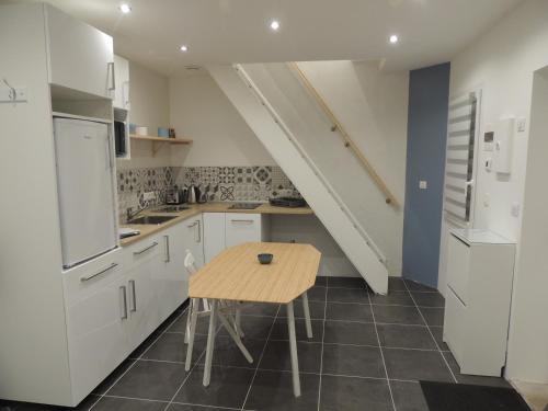 une cuisine avec des armoires blanches et une table en bois dans l'établissement Logement F1 neuf indépendant, à Belfort