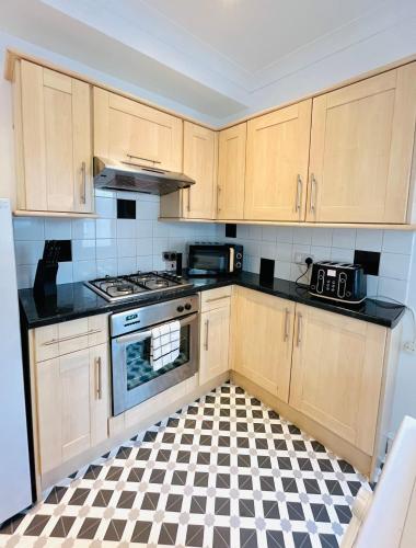 a kitchen with wooden cabinets and a checkered floor at Clarence Road in Portsmouth