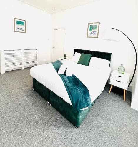 a bedroom with a large bed with white sheets and green blanket at Clarence Road in Portsmouth