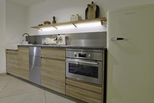 La cuisine est équipée d'une cuisinière en acier inoxydable et d'un réfrigérateur. dans l'établissement Superbe Appartement 1 chambre avec clim, terrasse et parking, à Montpellier