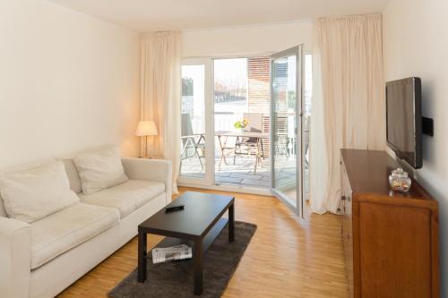 ein Wohnzimmer mit einem weißen Sofa und einem Tisch in der Unterkunft Heikotel - Hotel Am Stadtpark in Hamburg
