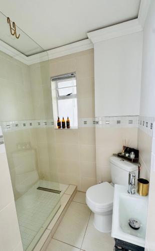 a white bathroom with a toilet and a sink at Cosy Family 2-Bedroom Cottage with Braai, Fireplace, Kitchen near Strand Beach in Strand