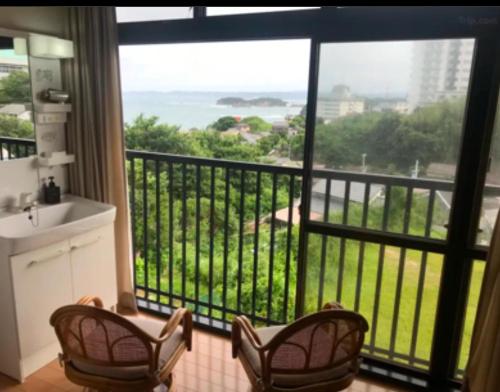 a bathroom with two chairs and a balcony with a view at 和みの宿いろり 甘露の湯付き in Shirahama