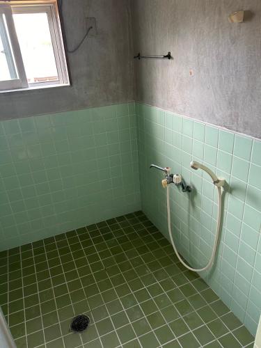 a green tiled bathroom with a shower in it at Kukaru クカル 伊平屋島の古民家一棟貸し in Gakiya