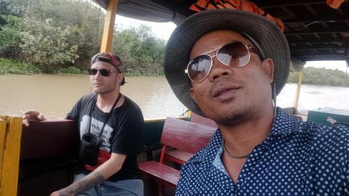 two men riding on a boat on a river at Kakrona Pouk Homestay in Siem Reap