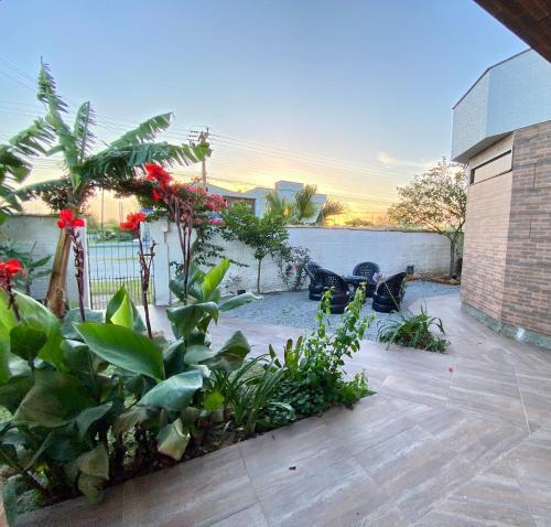 a garden with red flowers and plants on a patio at Apartamentos exclusivos e equipado com varanda ou terraço com Pôr do sol, cozinha privativa, Wi-Fi 600MBs, a 700m da praia de Itapirubá e 1km da BR-101 in Imbituba