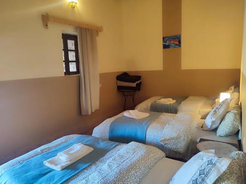 una habitación con tres camas y una ventana en Sahara Sands Hotel, en Merzouga