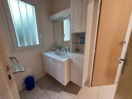 a white bathroom with a sink and a window at Villa PERICA pour 10 personnes. Entre lac et océan. Wifi gratuit. in Soorts-Hossegor