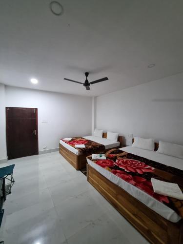 a room with two beds and a ceiling fan at Shivaji Inn Kaziranga in Kāziranga