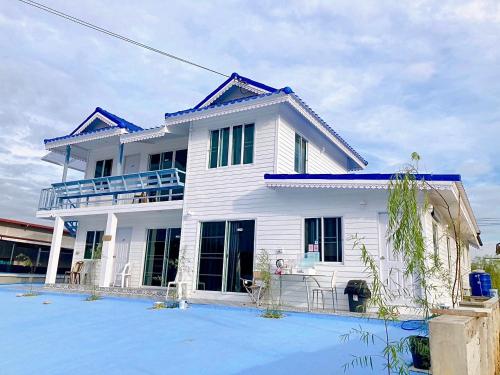 a white house with a blue roof at บ้าน ณัฐฐิญา โฮมสเตย์ Nattiya Homestay in Sathani Wat Suwan