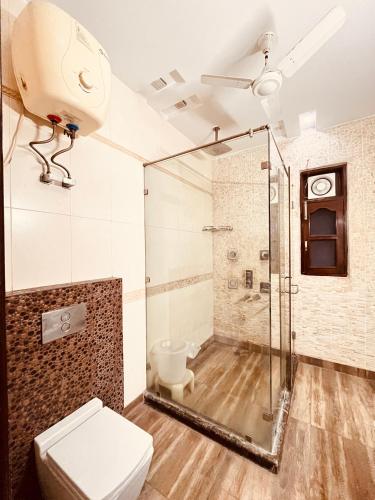 a bathroom with a glass shower and a toilet at South Inn - Green Park South Delhi in New Delhi