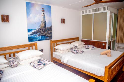 two beds in a room with a lighthouse picture on the wall at Cara Galle Fort in Galle