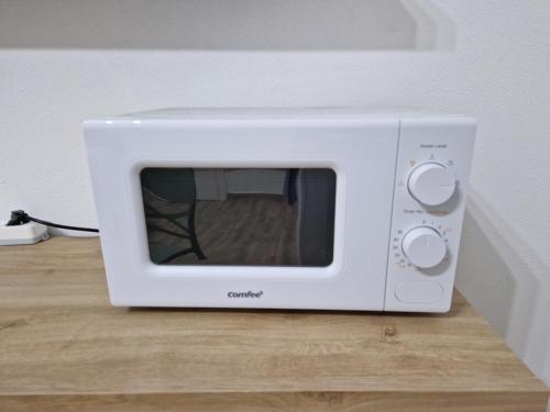 a white microwave sitting on top of a wooden table at Appartamento indipendente Clarò Guesthouse in Quartucciu