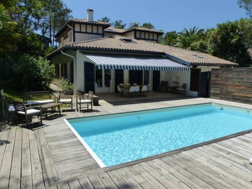 - une piscine sur une terrasse en bois avec une maison dans l'établissement Villa des Acacias avec piscine chauffée pour 15 personnes entre lac et océan Wifi gratuit, à Hossegor