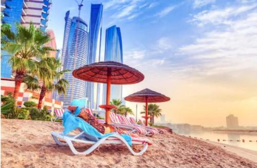 a group of chairs and umbrellas on a beach at Jaunty Stay Abu Dhabi in Abu Dhabi