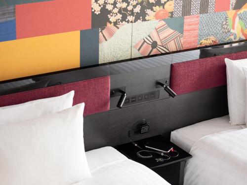 a hotel room with two beds and a painting on the wall at Mitsui Garden Hotel Kanazawa in Kanazawa