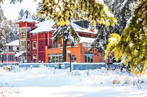 a large red building with snow on the ground at Villa Sokol in Borovets