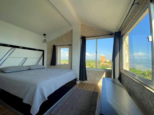 a bedroom with a large bed and large windows at Penthouse con Vista al Mar in Tucacas
