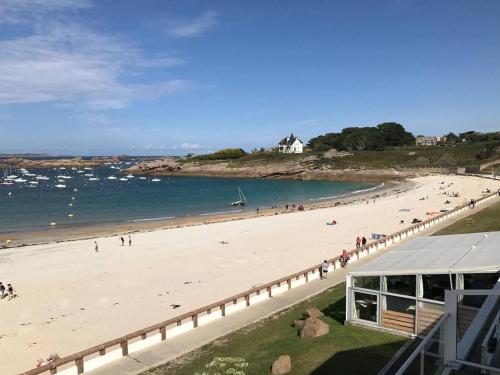 a beach with a group of people on it at Appartement rénové 3* avec jardin et WIFI à 20m de la plage - Trégastel - FR-1-368-77 in Trégastel
