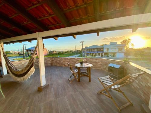 a porch with a hammock and a table and chairs at Apartamentos exclusivos e equipado com varanda ou terraço com Pôr do sol, cozinha privativa, Wi-Fi 600MBs, a 700m da praia de Itapirubá e 1km da BR-101 in Imbituba