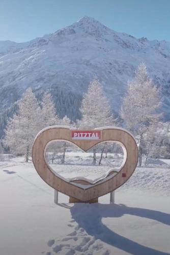 a bench in the snow with a mountain in the background at Ronalds Appartements in Sankt Leonhard im Pitztal