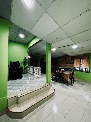 a living room with green walls and a table and chairs at Norvilla Homestay A in Pantai Cenang