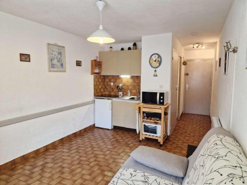un salon avec un canapé et une cuisine dans l'établissement T2 au cœur de Marseillan Plage avec terrasse, parking privé, proche commodités et animaux acceptés - FR-1-387-202, à Marseillan