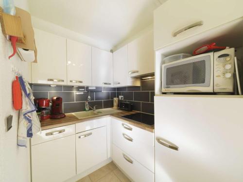une petite cuisine avec des armoires blanches et un micro-ondes dans l'établissement Spacieux appart 6 pers avec loggia à Gourette - FR-1-400-127, à Eaux-Bonnes