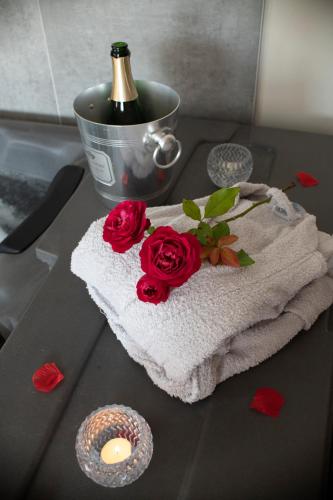 - une table avec une serviette, des roses et une bouteille de vin dans l'établissement Eden House, Cocon sensuel et romantique avec jacuzzi, à Carpentras