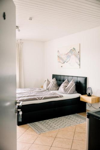 a bed with a black headboard in a bedroom at Gästehaus Fechtig in Hergensweiler