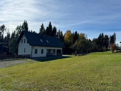 a white house on a hill with a green field at Dom na Mlaskawce in Istebna