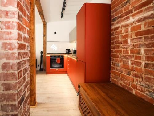 a kitchen with red cabinets and a brick wall at Brick and Wood Apartment in Bydgoszcz