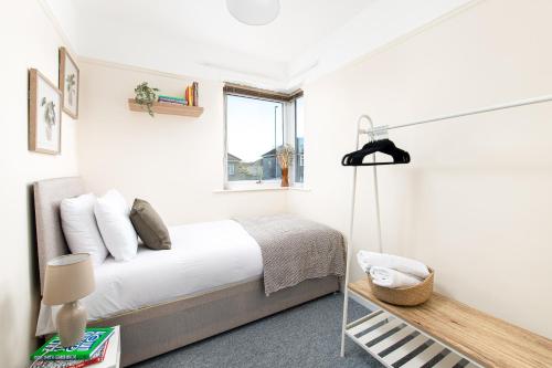 a white bedroom with a bed and a window at Long Stays-4bed house-Parking-By FabAccommodation in Bristol