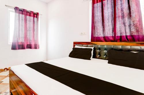 two beds in a room with red curtains at Hotel O Pragati Resort Marriage Hall & Restaurant in Gorakhpur